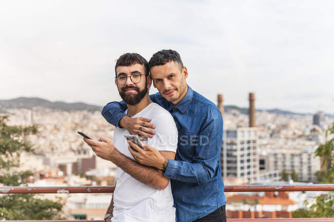 Retrato de casal gay feliz com smartphones, Barcelona, Espanha — Fotografia de Stock