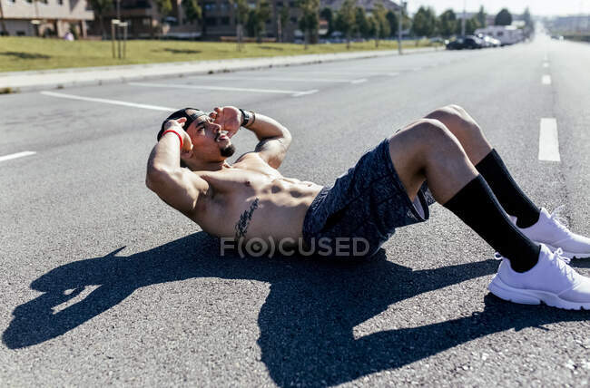 Молодой человек делает приседания на дороге — стоковое фото