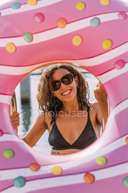 Retrato da mulher nova feliz atrás do flutuador inflável na forma do donut — Fotografia de Stock