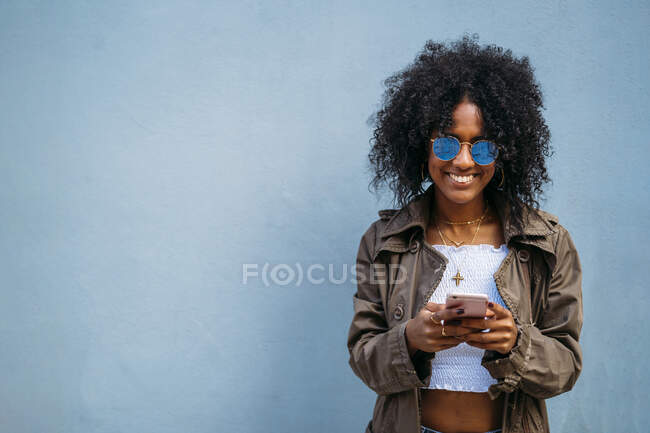 Mujer usando smartphone, fondo azul - foto de stock