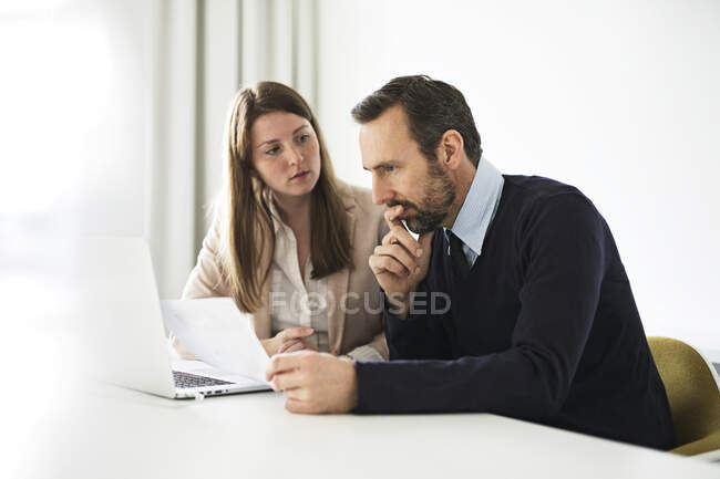 Businessman and employee with laptop and documents working at desk in office — Stock Photo