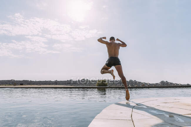 Young man jumping into water from a pier — Stock Photo