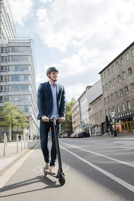 Junger Geschäftsmann mit E-Scooter auf Radweg in der Stadt — Stockfoto