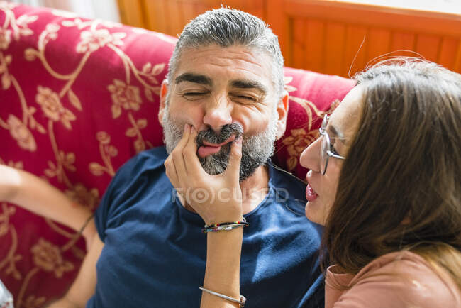 Mischievous daughter with father on couch at home — Stock Photo