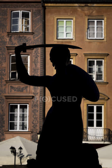 Polonia, Voivodato Masoviano, Varsavia, Silhouette della statua della sirena in piedi contro l'edificio residenziale del centro storico di Varsavia — Foto stock
