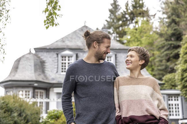 Sorridente giovane coppia nel giardino della loro casa — Foto stock
