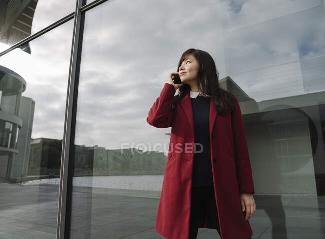 Donna d'affari in piedi vicino alla costruzione moderna e utilizzando smartphone — Foto stock