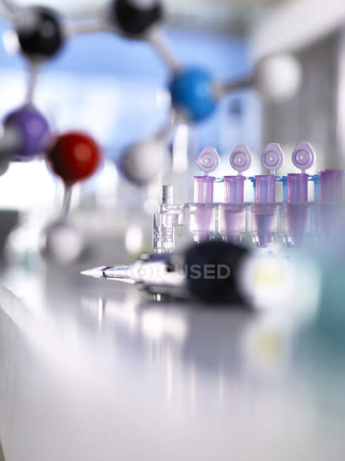 Close-up of pipette with molecular structure and test tubes on table in laboratory — Stock Photo