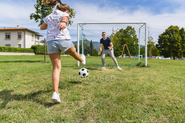 Padre e figlia che giocano a calcio su un prato — Foto stock