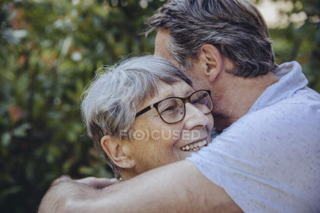 Hijo adulto abrazando a su madre en el jardín - foto de stock
