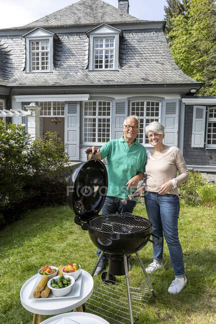 Heureux couple de personnes âgées ayant un barbecue dans le jardin de leur maison — Photo de stock