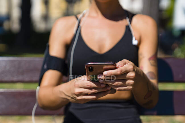 Primer plano de la joven deportista sosteniendo el teléfono celular - foto de stock