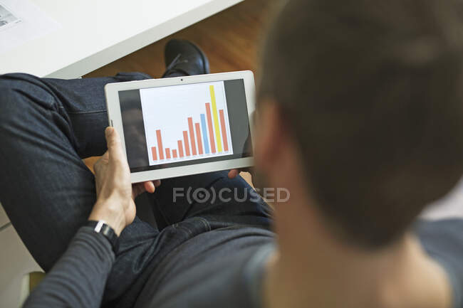 Geschäftsmann analysiert Balkendiagramm auf Tablet im Büro — Stockfoto