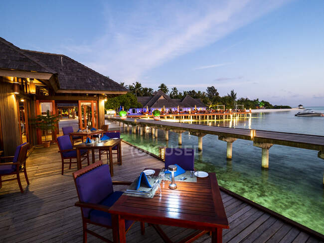 Maldives, Dining tables of coastal restaurant at dusk with pier in background — Stock Photo
