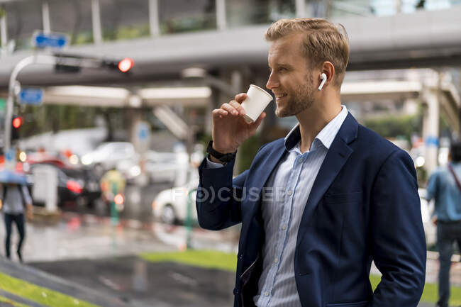 Young businessman with coffee to go in Bangkok during a rainy day — Stock Photo