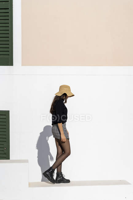 Молода жінка з сонцезахисним капелюхом і білою стіною. — стокове фото