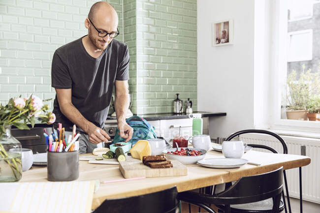 Mann packt in Küche Snacks für Mittagspause ein — Stockfoto