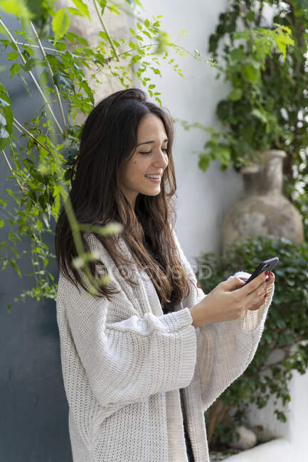 Young woman wearing cardigan and using smartphone — Stock Photo