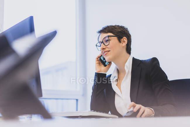 Junge Geschäftsfrau telefoniert am Schreibtisch im Büro — Stockfoto