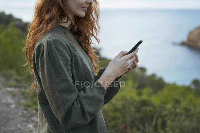 Jovem ruiva usando telefone celular na costa, Ibiza, Espanha — Fotografia de Stock