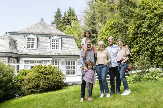 Happy extended family standing in garden of their home — Stock Photo