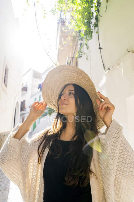 Giovane donna che indossa il cappello da sole e guarda in alto, contro il sole — Foto stock