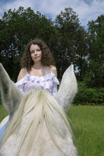 Portrait of young woman sitting on horse on a meadow — Stock Photo