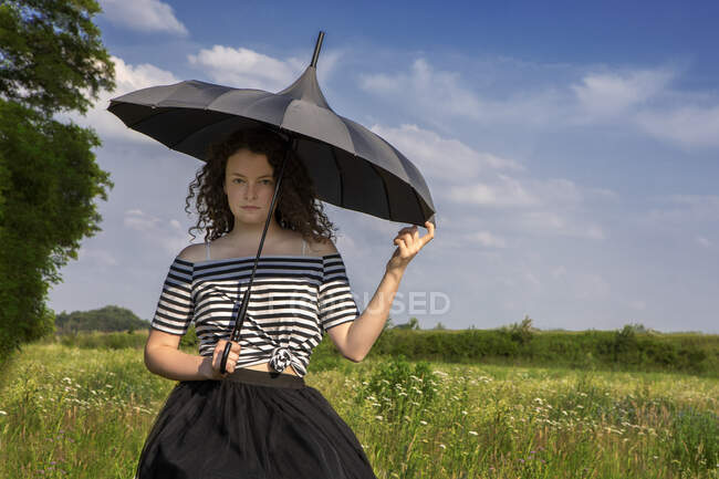 Retrato de mujer joven con paraguas en un prado - foto de stock