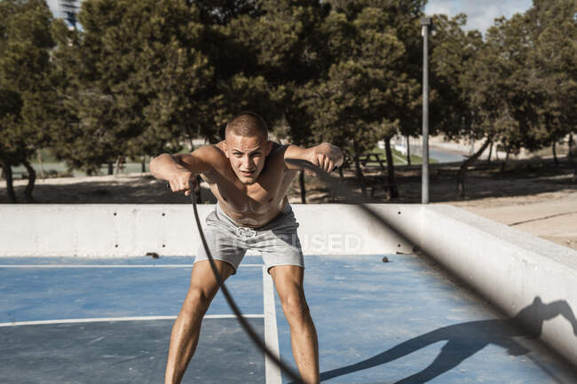 Заварювальний мускулистий чоловік бігає з бойовими мотузками на відкритому повітрі. — стокове фото