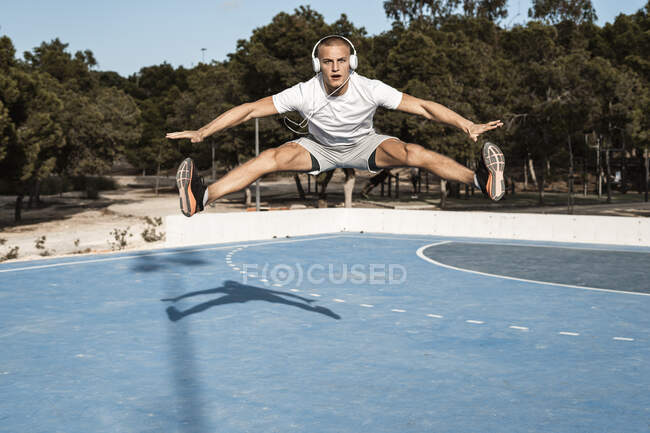 Giovane uomo con le cuffie saltare all'aperto — Foto stock