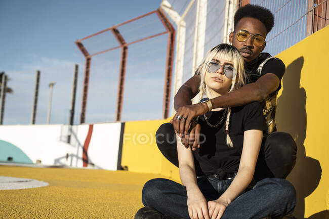 Portrait of young couple wearing coloured sunglasses — Stock Photo