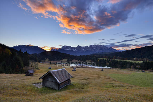 Vista panorámica de cabañas de madera contra el lago Geroldsee y las montañas Karwendel durante el amanecer en Baviera, Alemania - foto de stock