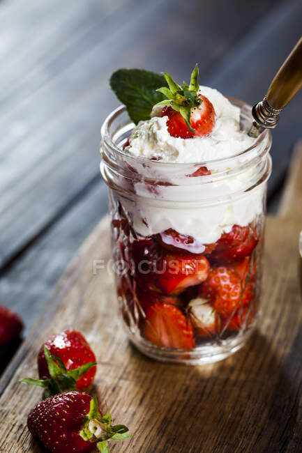 Jar of fresh strawberries with whipped cream — Stock Photo