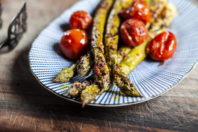 Grilled green asparagus with cherry tomatoes on a plate — Stock Photo