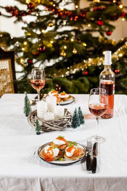 Blinis with sour cream, smoked salmon and fish roe, in front of Christmas decoration — Stock Photo