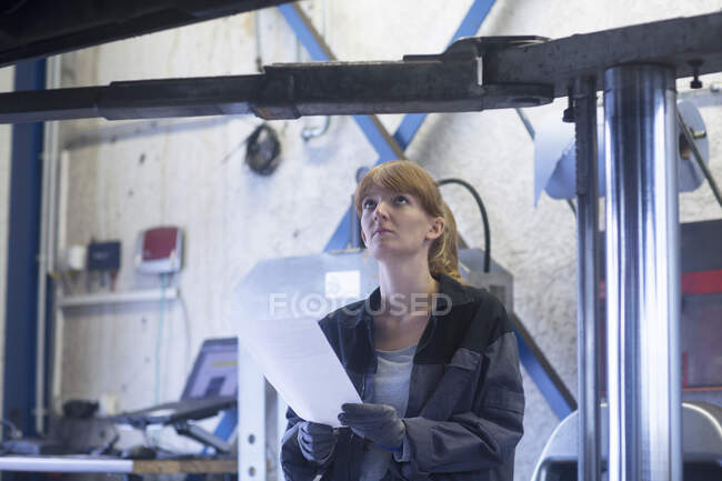 Female car mechanic looking to bottom of a car in repair garage — Stock Photo
