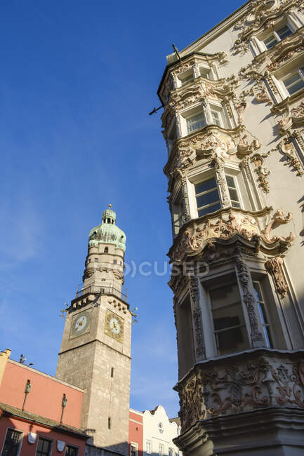 Low angle view of Stadtturm and Helbling House against blue sky at Innsbruck, Austria — Stock Photo