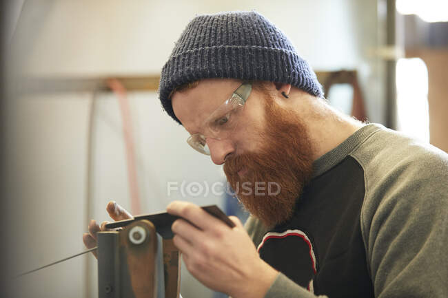 Hombre haciendo cuchillos en un taller - foto de stock