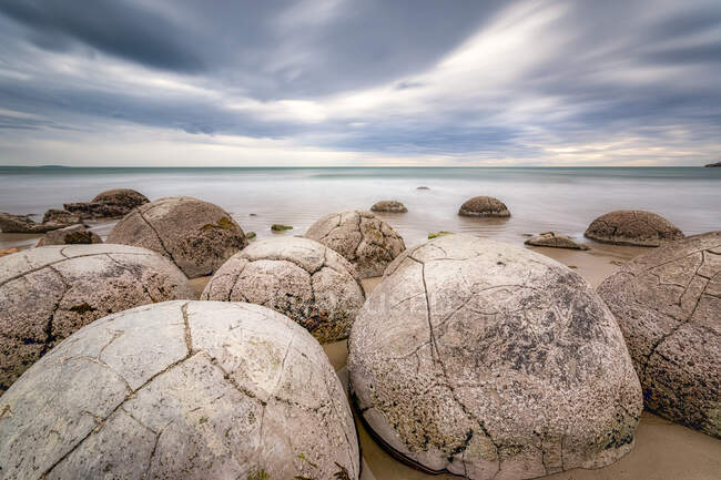 Moeraki Boulders на березі проти хмарного неба на пляжі Koekohe Beach, South Island, New Zealand — стокове фото