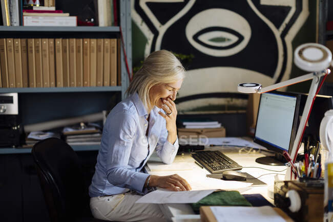 Mature woman working in architct's office, checking floor plans — Stock Photo