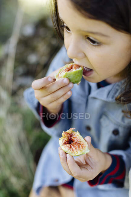 Niño comiendo un higo al aire libre - foto de stock