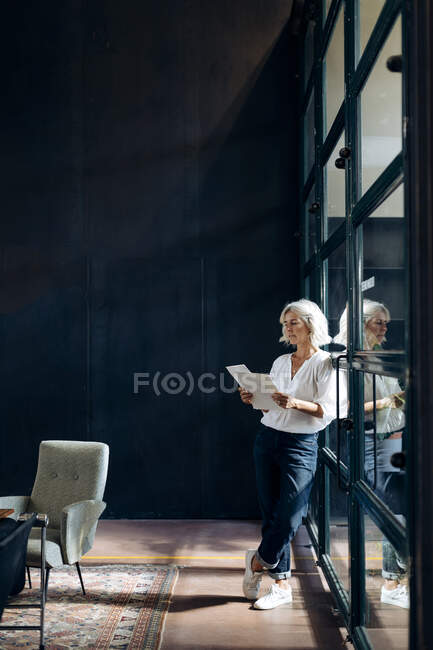 Казуальна зріла бізнес-леді розглядає документи в офісі лофт — стокове фото