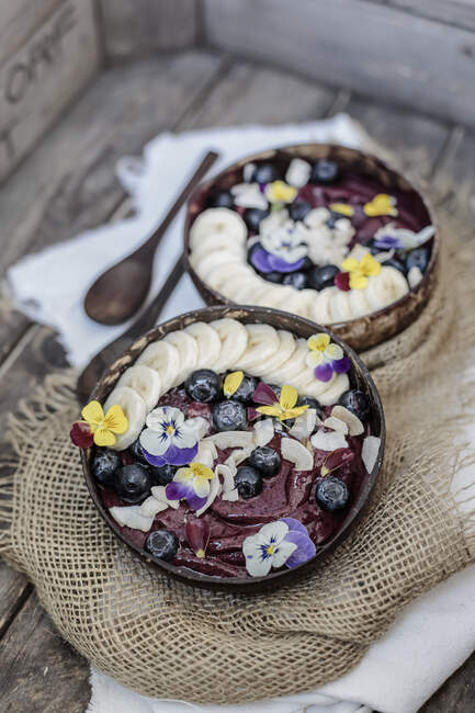 Vista de alto ângulo de sorvete decorado com frutas e flores servidas em tigelas na mesa — Fotografia de Stock