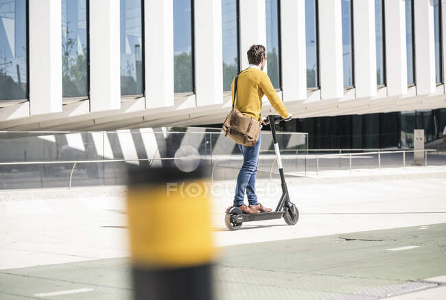 Young man riding e-scooter in the city — Stock Photo