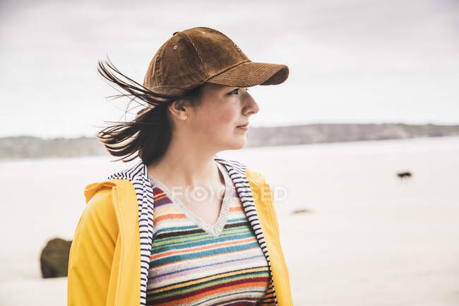 Портрет молодой женщины в желтой дождевой куртке на пляже, Бретань, Франция — стоковое фото