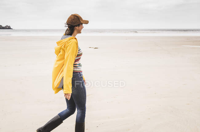 Giovane donna in giacca da pioggia gialla in spiaggia, Bretagne, Francia — Foto stock