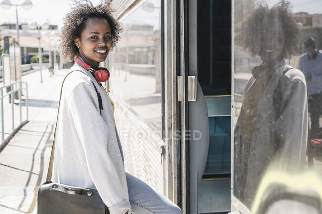 Portrait of a smiling young woman entering a train — Stock Photo