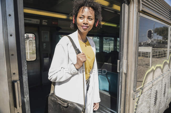 Sonriente joven mujer de pie en la puerta del tren - foto de stock