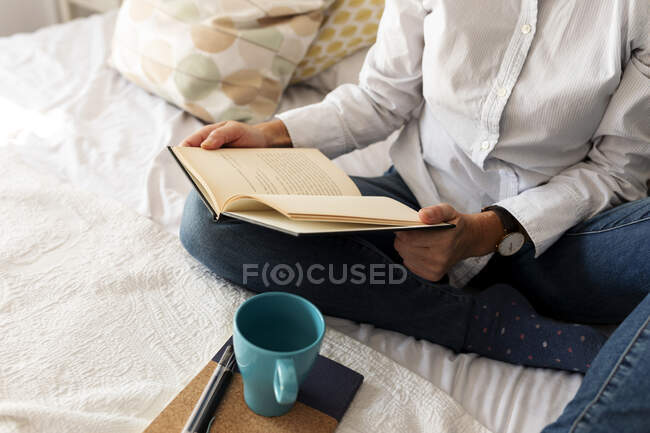 Primo piano di donna con libro seduto sul letto a casa — Foto stock
