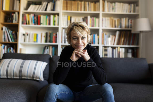 Porträt einer lächelnden reifen Frau, die zu Hause auf der Couch sitzt — Stockfoto